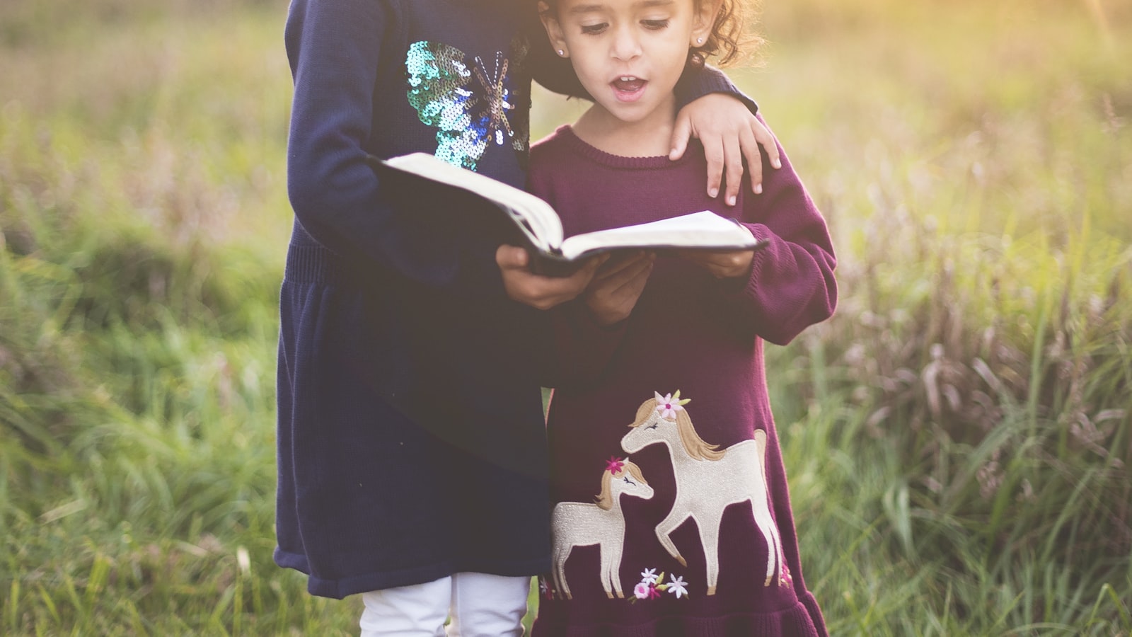 A parent crouching down to eye level to speak with a young child outdoors.