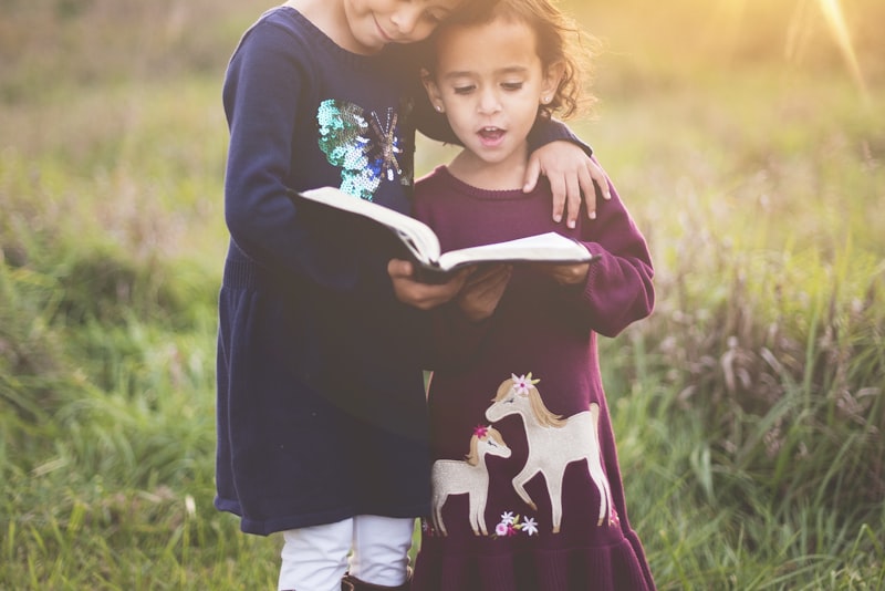 A parent crouching down to eye level to speak with a young child outdoors.